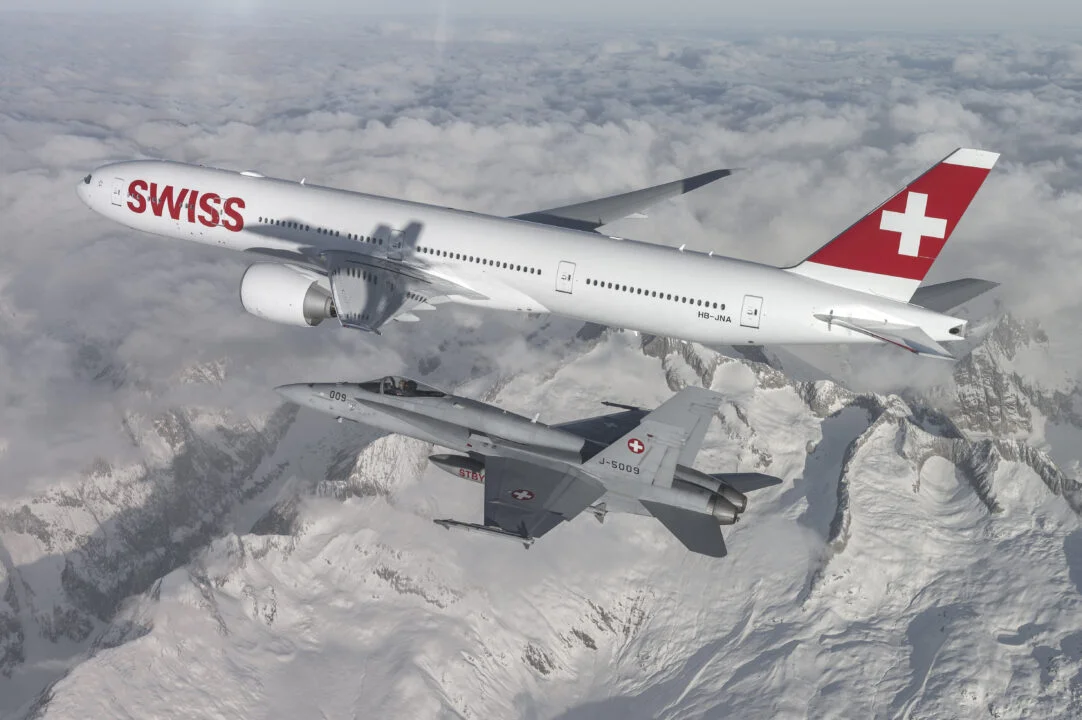 Ein Kampfjet der Schweizer Armee fliegt mit einem Swiss-Linienflugzeug über die Schweizer Alpen.